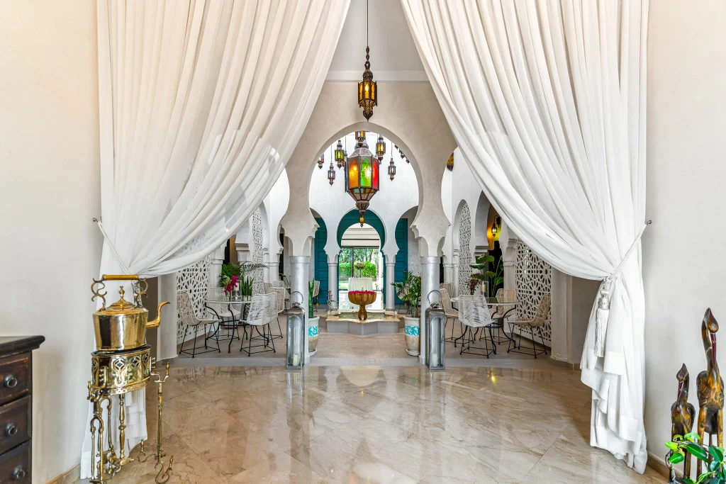 Luxurious lounge with Moroccan arches, white drapes, and colorful lanterns.