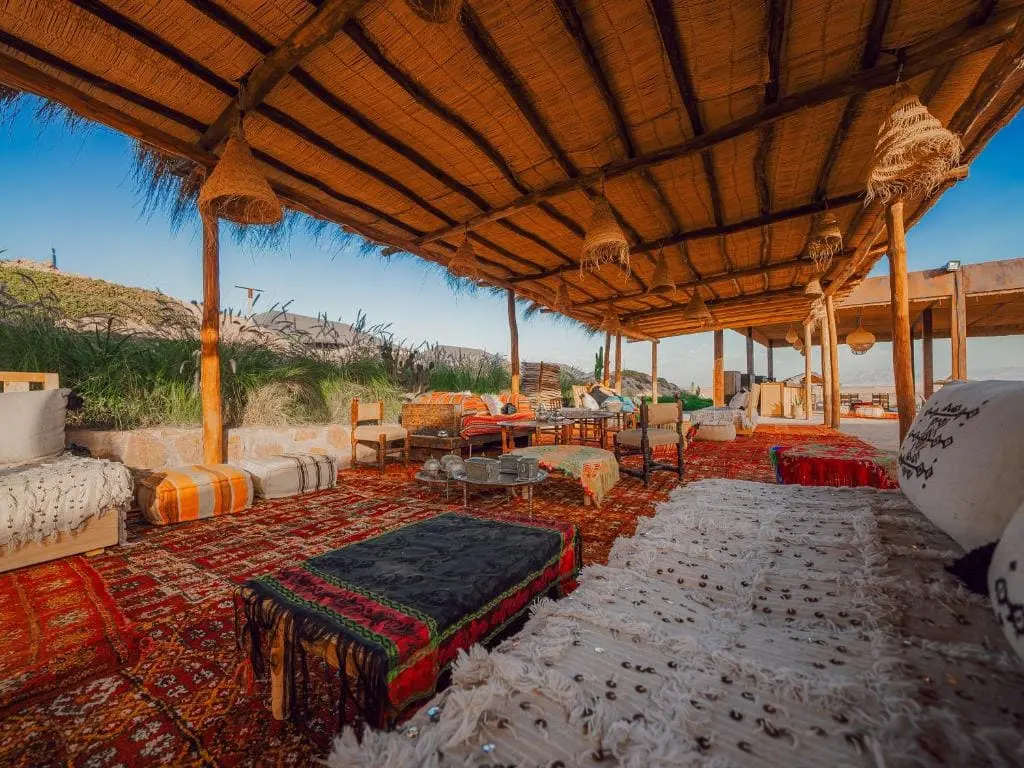 Outdoor lounge area with cushions, rugs, and a thatched roof at Locanda Boutique Collection.