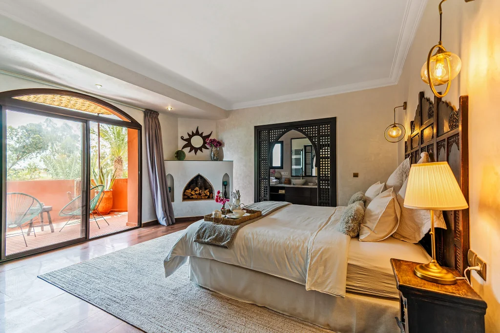Elegant bedroom with balcony, modern decor, and warm lighting.