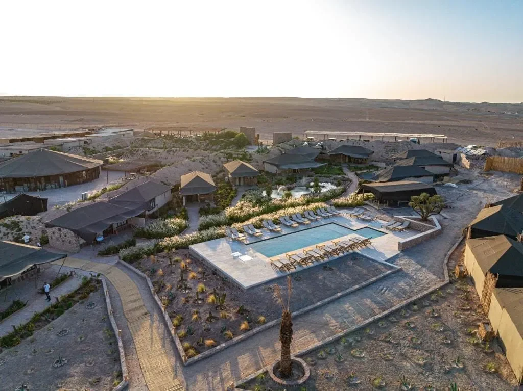 Luxury resort with pool and surrounding villas in a desert landscape.