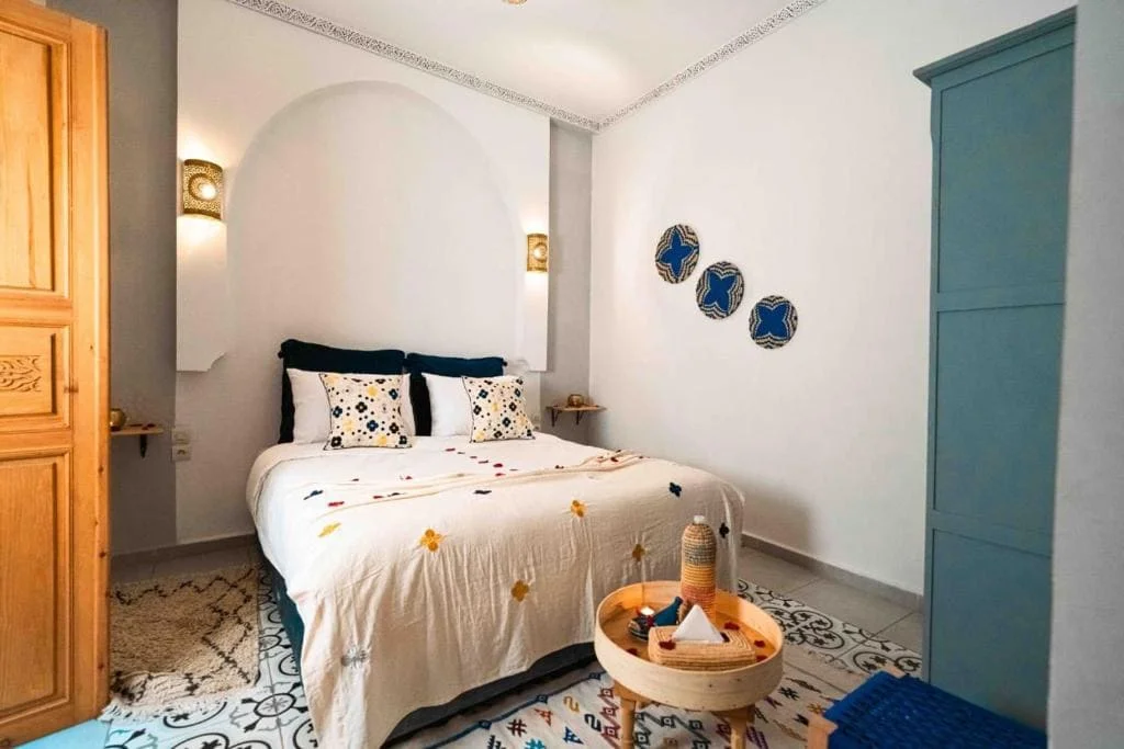 Elegant bedroom with white bedding, blue accents, and Moroccan decor.