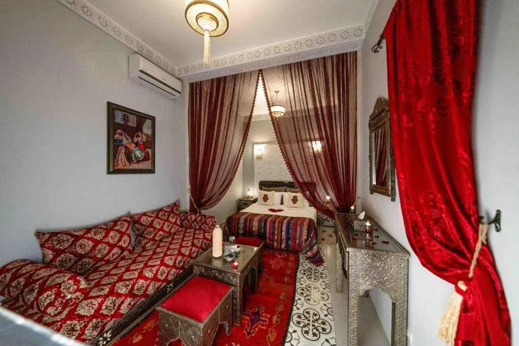 Luxurious bedroom with ornate furniture and rich red curtains in Marrakech riad.