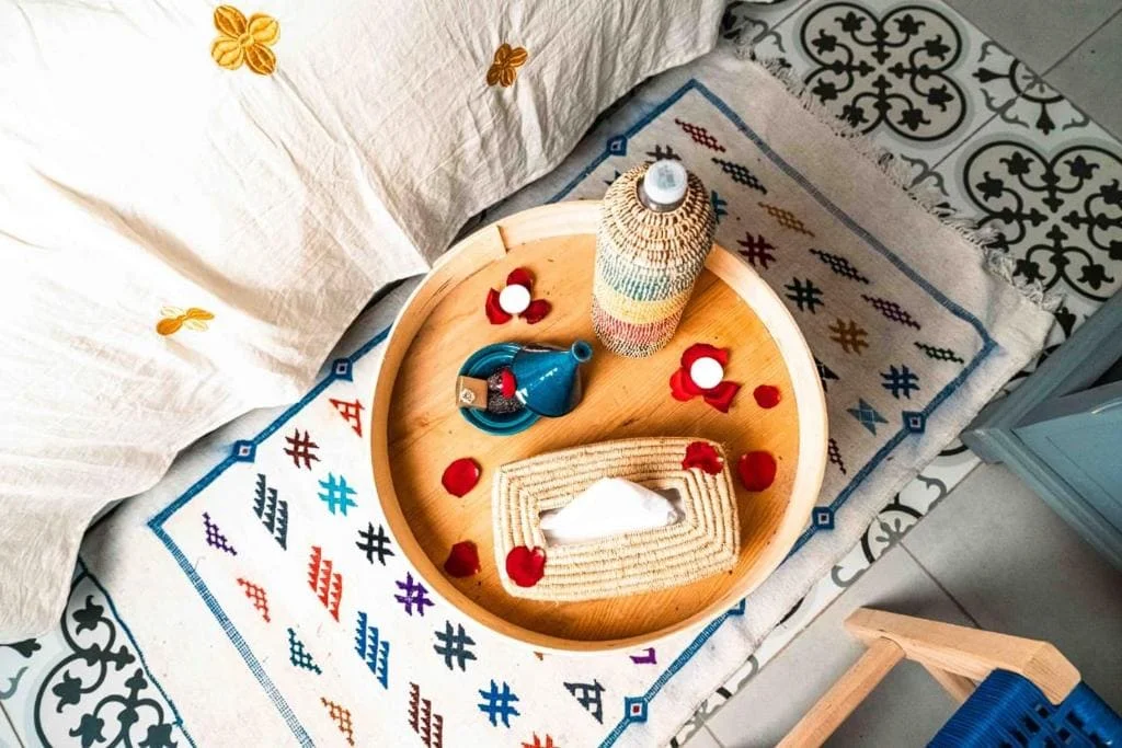 Decorative tray with candles, soap, and a bottle on a patterned rug.