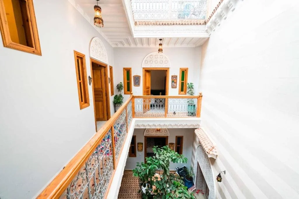 Elegant Moroccan riad interior with intricate woodwork and lush greenery.