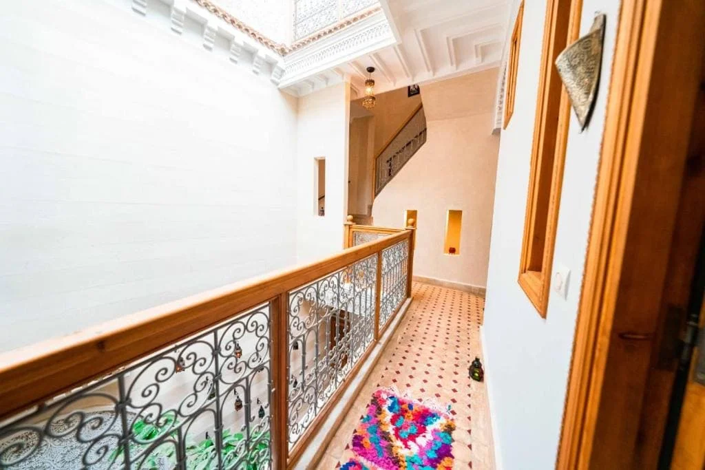 Balcony view at Riad Kiyanjana Marrakech with ornate railing and colorful rug.