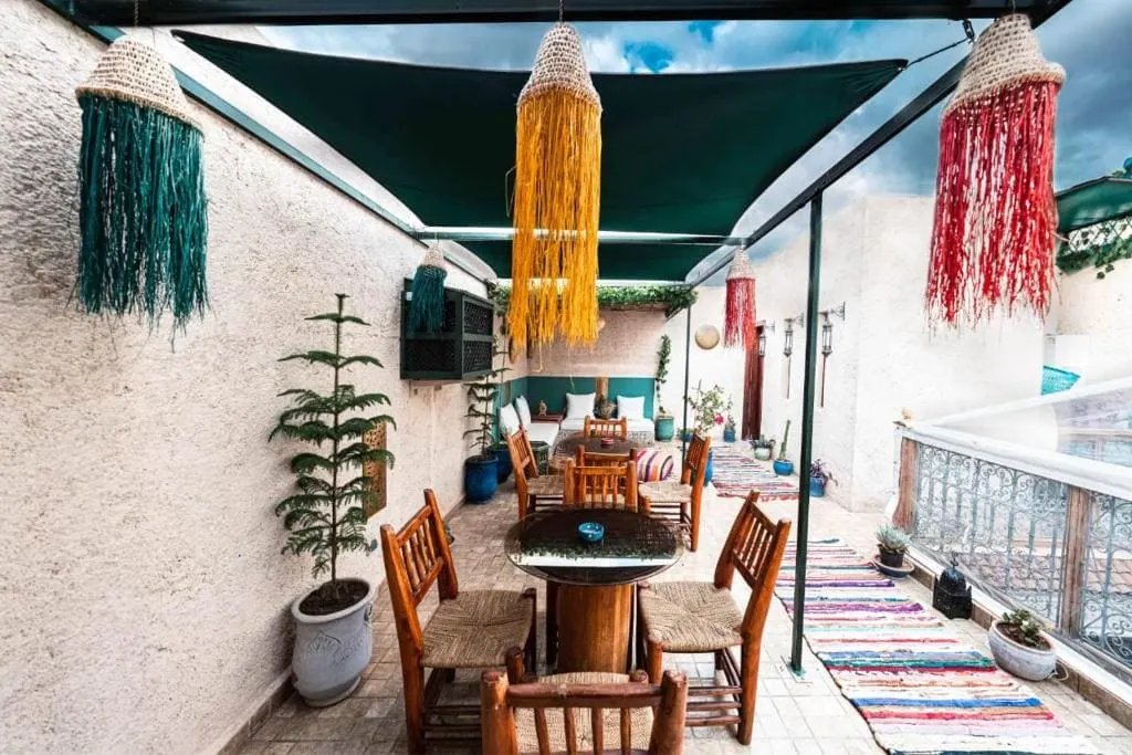 Outdoor patio at Riad Kiyanjana Marrakech with colorful hanging decorations.