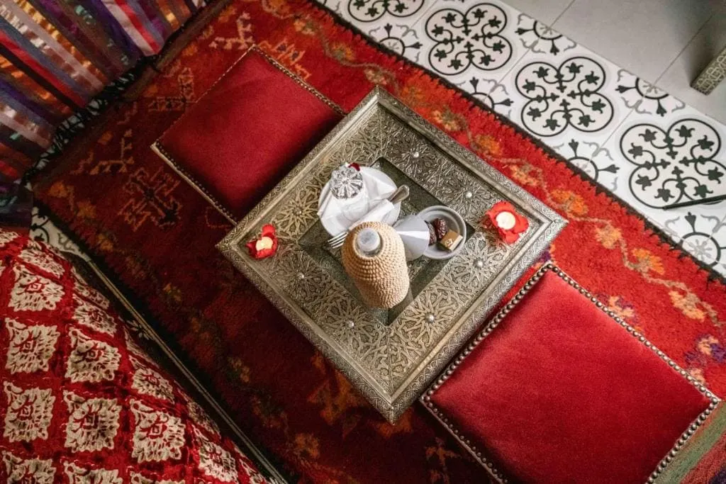 Elegant Moroccan-inspired interior with red cushions and ornate silver tray.