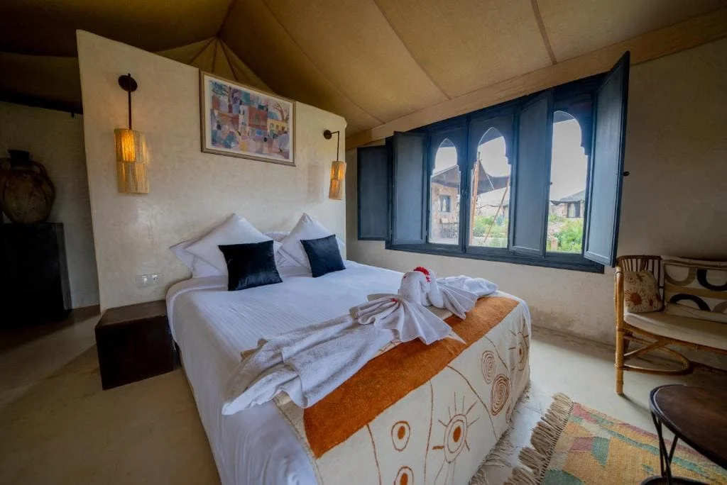 Cozy bedroom with a large bed, decorative towels, and scenic window view.